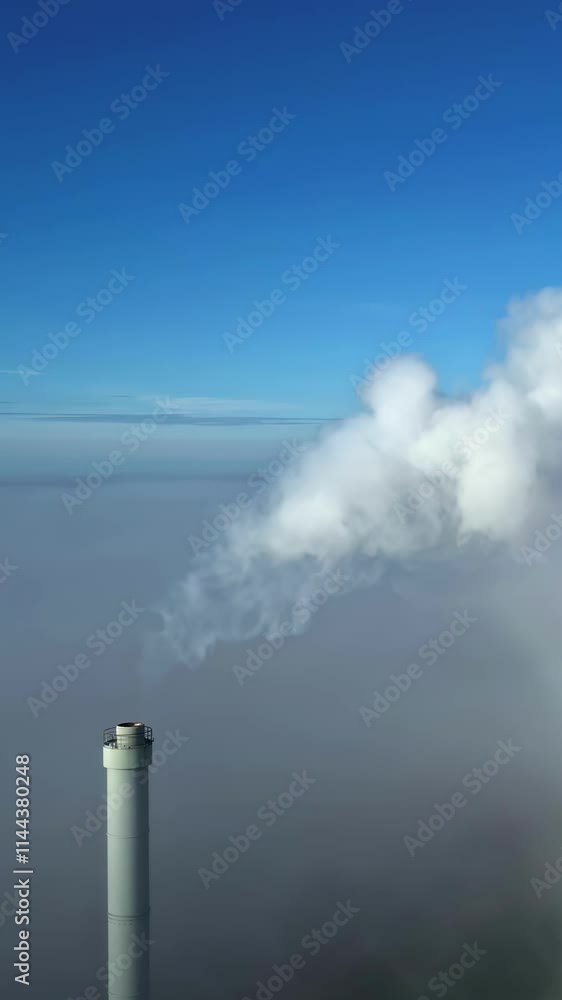 Vertical shot of a factory chimney, waste air spreads in the sky, air pollution caused by industry, climate change, slow motion, truck shot to the right, copy space Vertical shot of a factory chimney, waste air spreads in the sky, air pollution caused by industry, climate change, slow motion, truck shot to the right, copy space