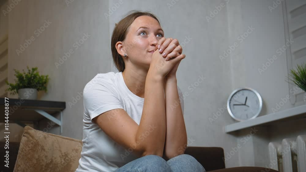 Young woman sitting on sofa, expressing excitement and joy while watching TV in cozy, living room in evening, enjoying personal entertainment and leisure Young woman sitting on sofa, expressing excitement and joy while watching TV in cozy, living room in evening, enjoying personal entertainment and leisure