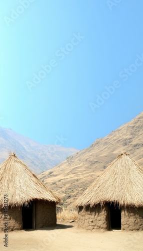 Two traditional thatched huts in a rural landscape under a clear sky.