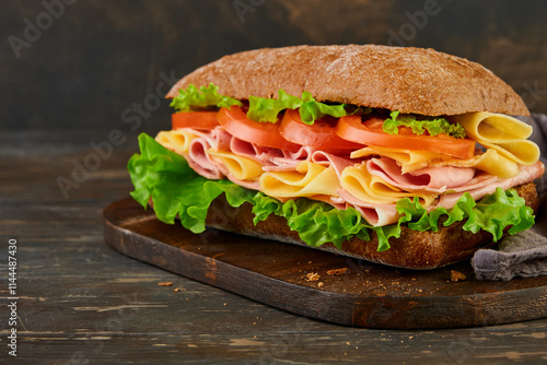 Sandwich. One fresh big submarine sandwich with ham, cheese, lettuce, tomatoes and microgreens on old wooden dark background. Healthy breakfast theme concept, school lunch, breakfast or snack. photo