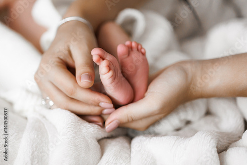 A baby's feet are being held by a mother and father. The baby is small and has a pink color. Concept of warmth and love between the parents and their child