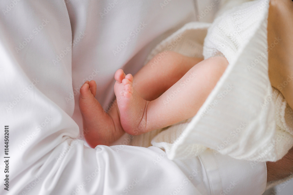 A baby's foot is held in a white blanket. The baby is likely to be a newborn A baby's foot is held in a white blanket. The baby is likely to be a newborn
