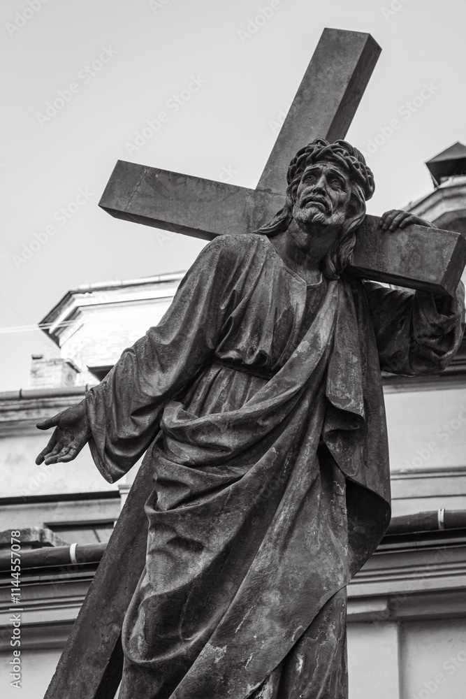 Obraz premium Sculpture of Jesus Christ with cross, black and white. Ancient monument of Jesus Christ in Lviv, Ukraine. Faith and sorrow concept. Old religious monument. Faith symbol and sign.
