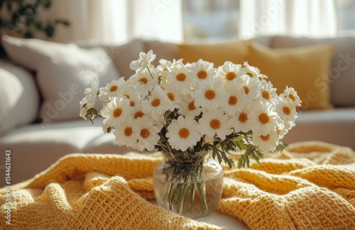 Bright daisies in a clear vase bring freshness to a cozy living room with bri...