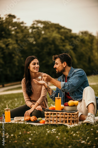 Φωτογραφία Man and woman enjoying drinks and finger foods at a park picnic