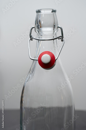 Close up of an old fashioned clear swing top bottle is standing on a dark table, in front of a white background. Copy space. Vertical shot. photo