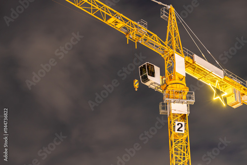Crane at construction site at night around Christmas time, seen from below A huge christmas star is attached to the crane.
