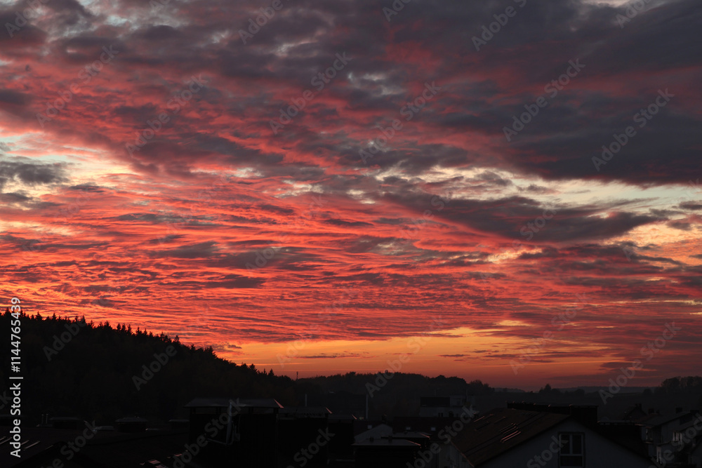 Orange, red sunset over forest and village. Romantic dramatic background for design. Sky and clouds. Orange, red sunset over forest and village. Romantic dramatic background for design. Sky and clouds.