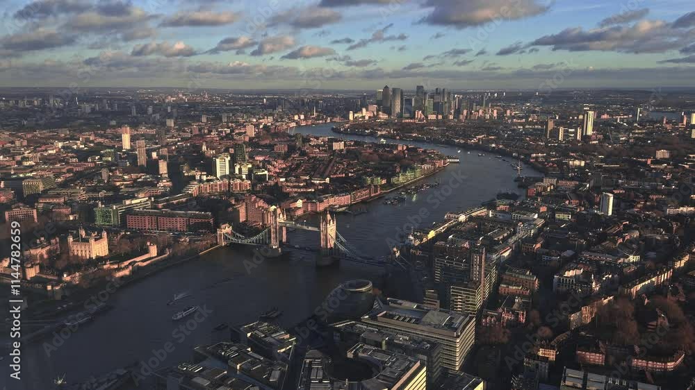 Aerial perspective of Tower Bridge over the River Thames with London's skyline, featuring historic and modern architecture in warm, golden light.