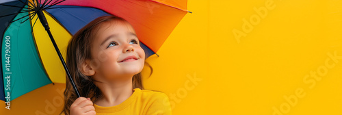 A joyful child looks up, holding a vivid rainbow umbrella against a bright yellow backdrop, symbolizing innocence and happiness in a playful, vibrant scene.
