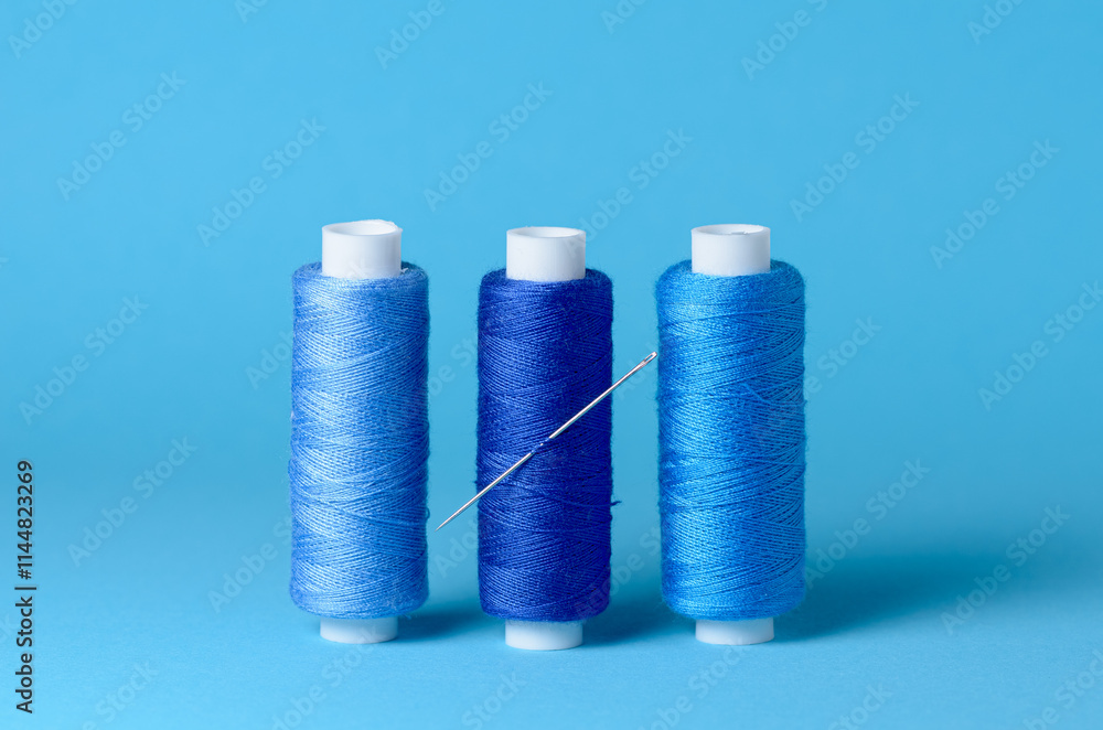 Row of blue thread spools with needle aligned background with copy space for text close-up flat lay top view Row of blue thread spools with needle aligned background with copy space for text close-up flat lay top view