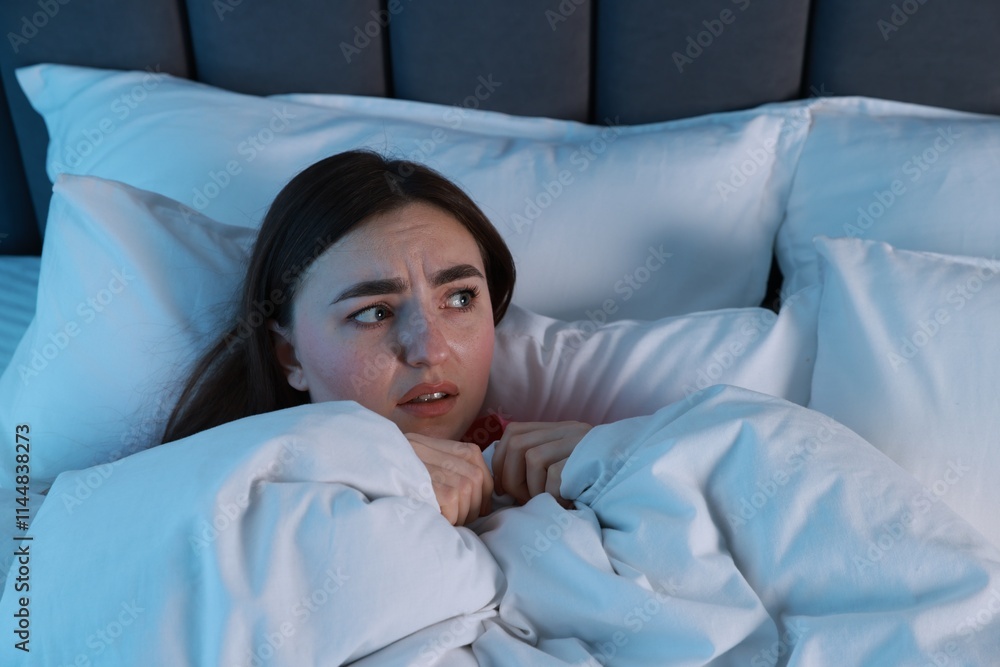 Fear of darkness. Scared young woman lying on bed in room at night, space for text Fear of darkness. Scared young woman lying on bed in room at night, space for text