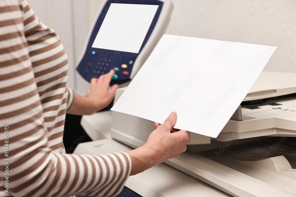 Woman with paper sheet using modern printer indoors, closeup. Printing house Woman with paper sheet using modern printer indoors, closeup. Printing house