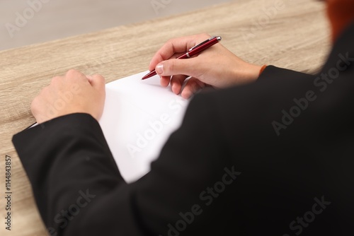 Writer signing autograph in book at wooden table indoors, closeup photo