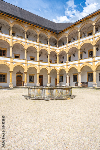 Elegant architecture and historical charm of Velke Losiny Chateau courtyard, featuring arched columns and a central fountain under a bright blue sky in Czechia. photo