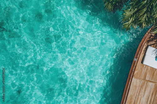 A scenic perspective from a wooden deck looking over crystal clear turquoise water with palm trees casting shadows, suggesting a paradise-like tropical setting. photo