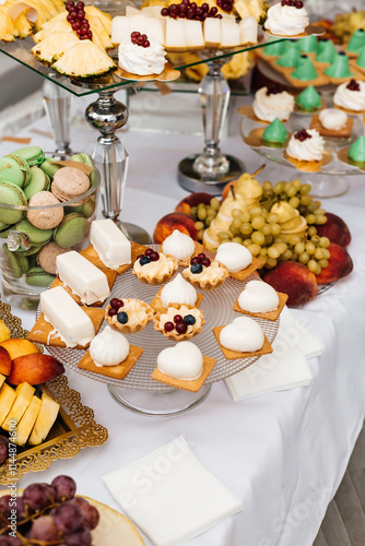 table with desserts. In the foreground is a glass plate with small tartlets photo