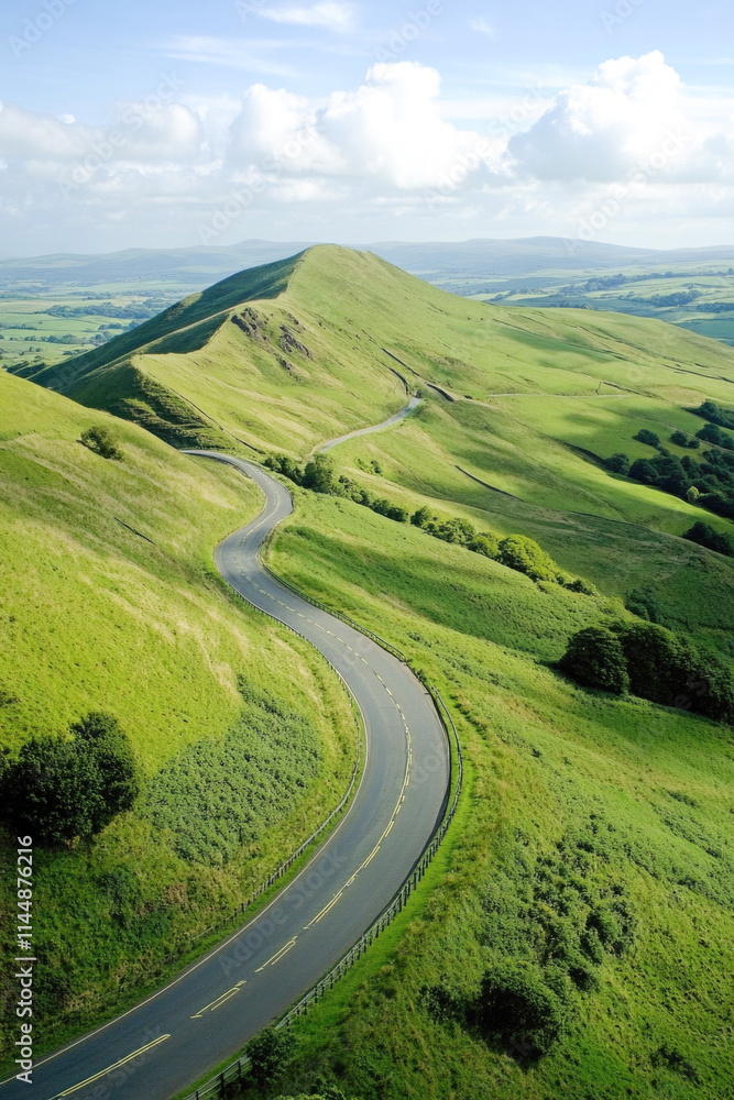Fototapeta premium Serene winding road through lush green hills under blue skies