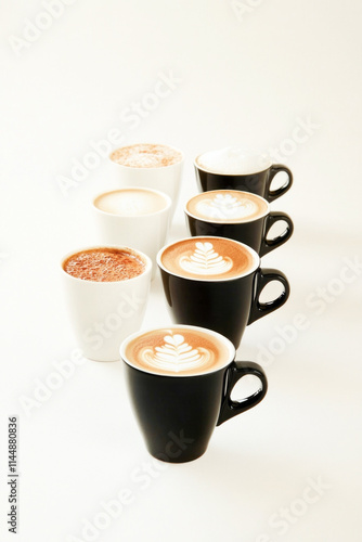 Variety of cappuccino and latte art in black and white mugs