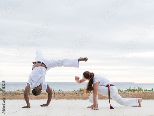 A couple doing capoeira exercise near an ocean view
