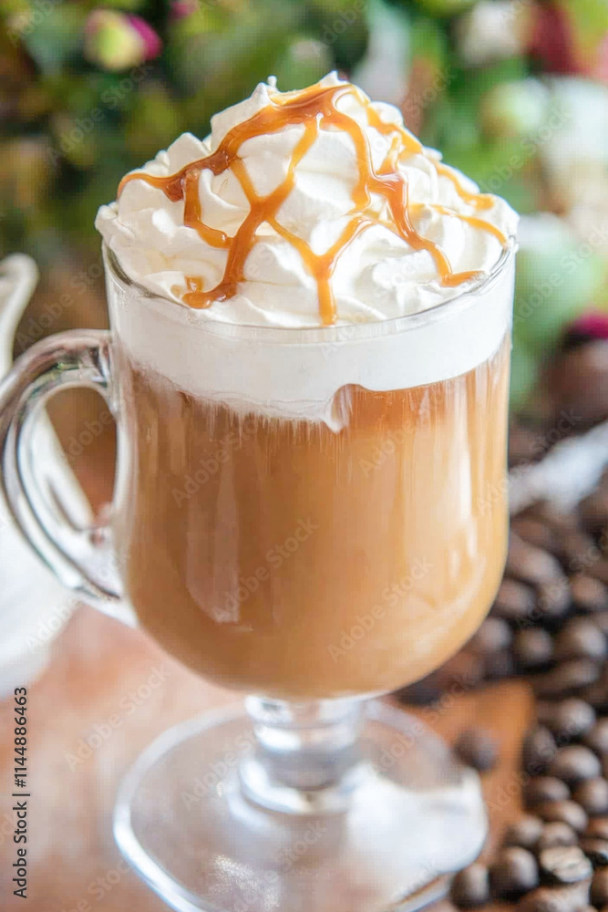 Caramel drizzled whipped cream coffee in glass mug surrounded by coffee beans Caramel drizzled whipped cream coffee in glass mug surrounded by coffee beans