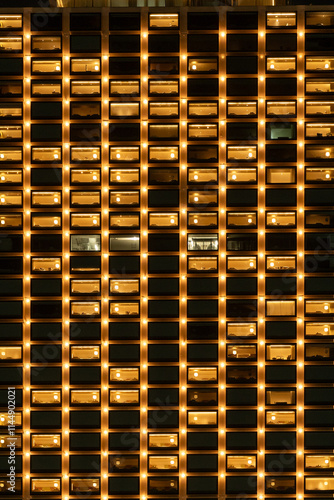 Brightly lit apartment building facade at night, showcasing illuminated windows