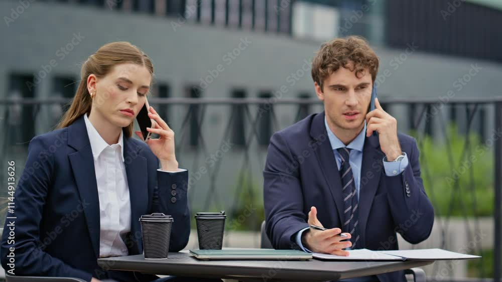 Worried coworkers negotiating phone call sitting outdoors restaurant closeup.