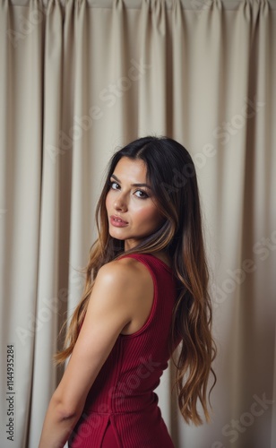 A woman in a red dress standing in front of a curtain