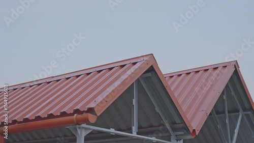 Wallpaper Mural Vivid red corrugated metal roofing with structural gutters standing against serene blue sky, highlighting industrial architectural precision and geometric design Torontodigital.ca