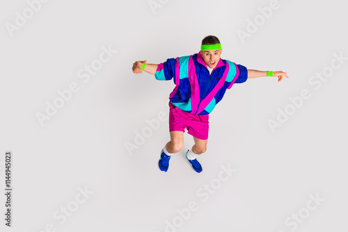 Young man in colorful retro sportswear striking a dynamic pose on white backdrop photo