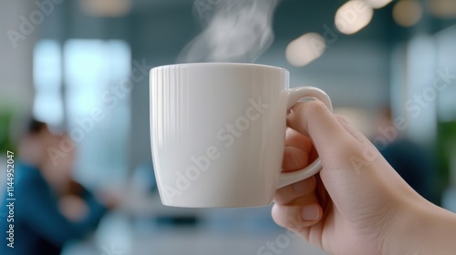  hand holding a steaming cup of coffee in an office lounge