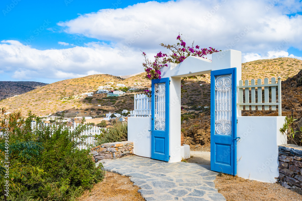 Decorated with flowers entrance gate to typical Greek style holiday apartments in Katapola village