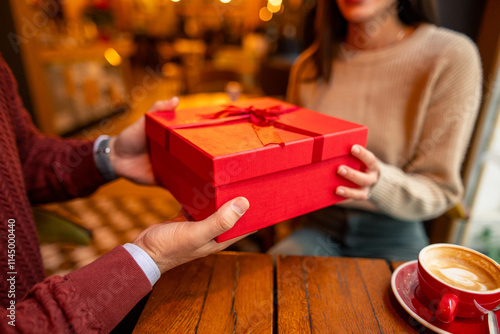 Photography A mid adult Caucasian male surprises his spouse with a gift in a cozy cafe setting