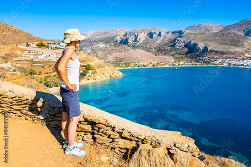 Obraz na płótnie Woman tourist standing on high cliff and looking at Hochlaka beach in Aigiali bay (Ormos Egialis), Amorgos island, Cyclades, Greece w salonie