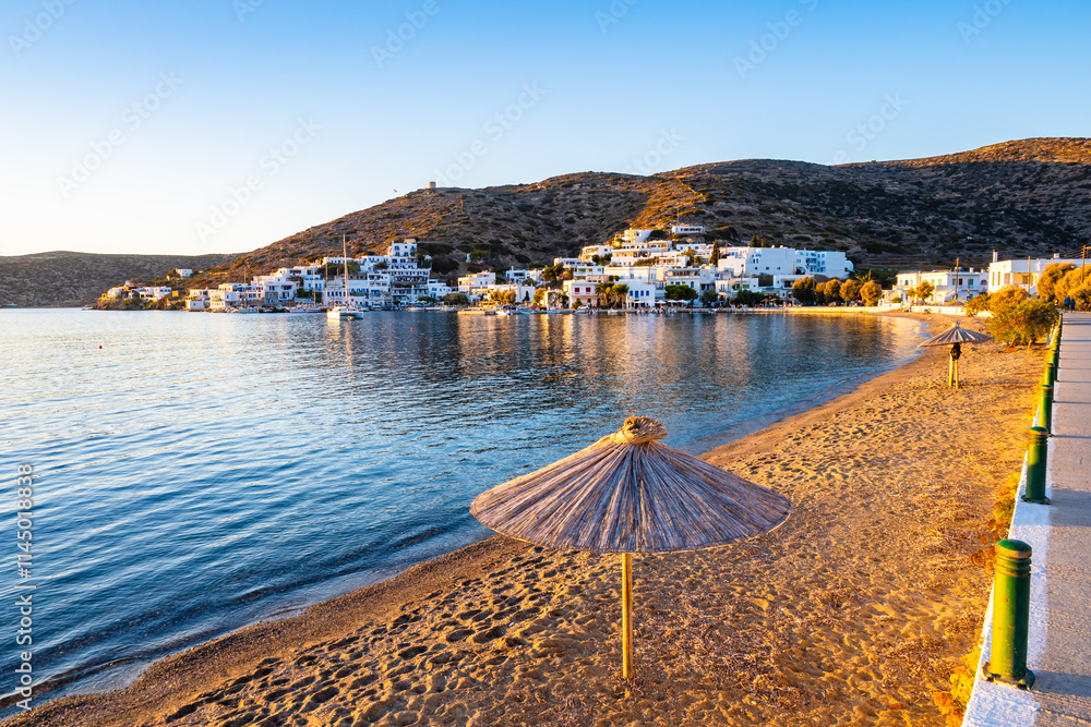 Sun umbrella on sandy beach in Katapola port at sunset, Amorgos island, Cyclades, Greece