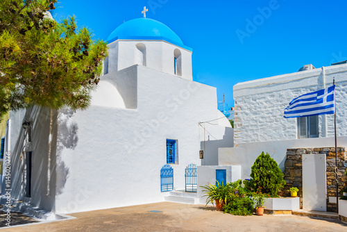 Church on square with Greek flag in Lagada village, Amorgos island, Cyclades, Greece