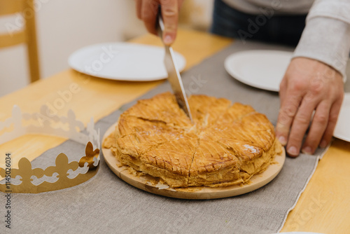 A young man cuts a royal galette at the table. photo