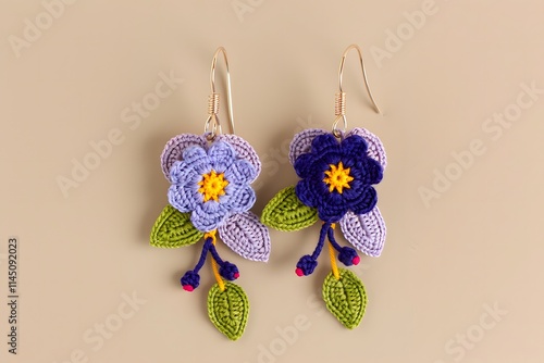Handmade blue and purple flower earrings with green leaves and gold hooks, close-up on a beige background, highlighting intricate floral craftsmanship.

