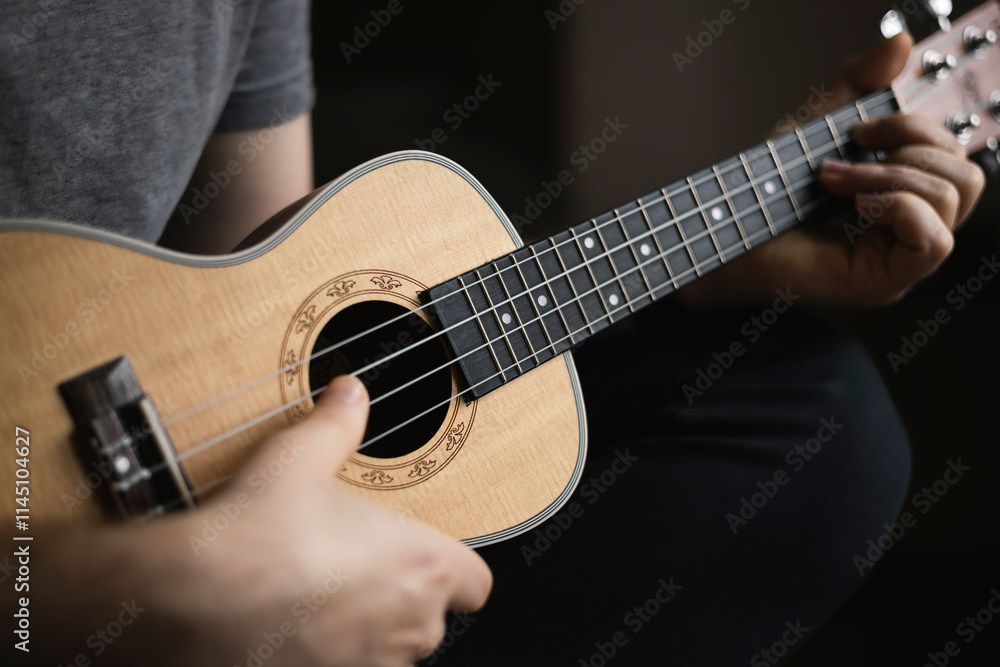 Man learns to play the ukulele. The concept of online learning, home education. Man learns to play the ukulele. The concept of online learning, home education.