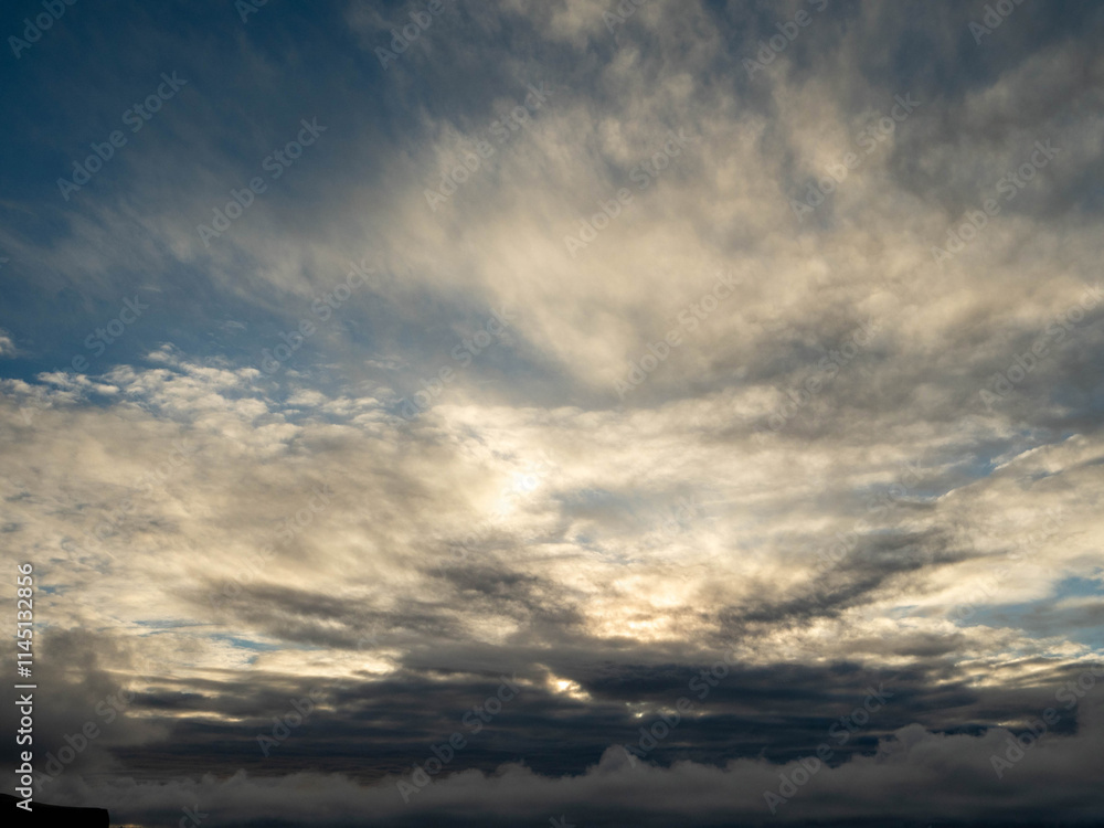 The sky is filled with fluffy clouds, and the sun is peeking through them, creating a beautiful and calming scene. The clouds are scattered throughout the sky, with some closer to the horizon The sky is filled with fluffy clouds, and the sun is peeking through them, creating a beautiful and calming scene. The clouds are scattered throughout the sky, with some closer to the horizon