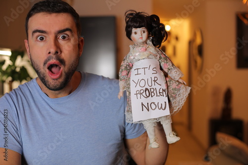 Terrified man holding a porcelain haunted doll  photo