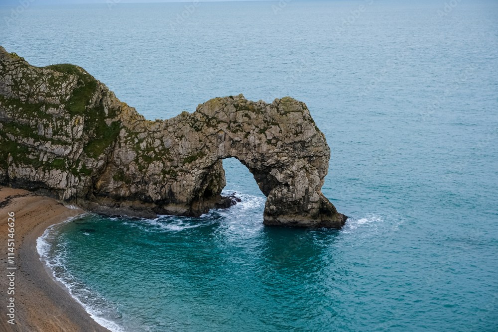 Fototapeta premium Durdle Door limestone arch on the Jurassic Coast in Dorset. Natural landmark. England. Pure clean clear water. Winter cold day at Durdle Door in Dorset, England, UK