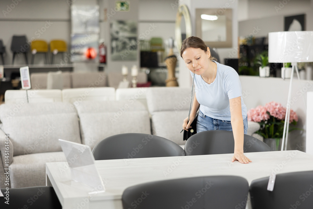 Satisfied woman chooses new modern table in a furniture store Satisfied woman chooses new modern table in a furniture store