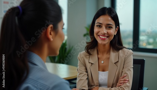 Indian businesswoman recruiter smiles during job interview. Applicant sits opposite. Pro business meeting in office. Formal setting. Happy conversation. Successful recruitment process. Candidate