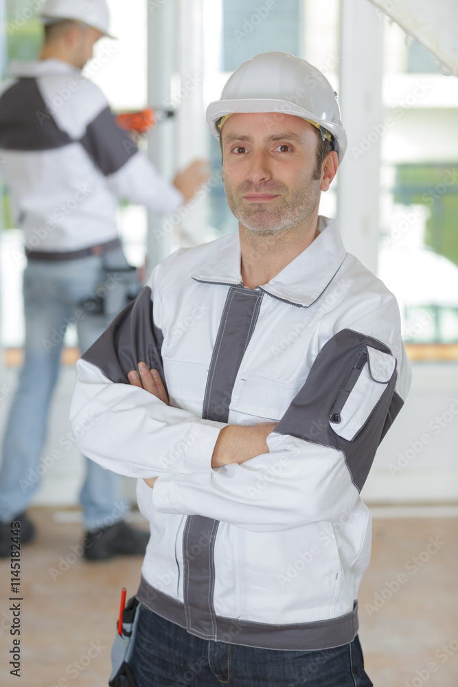 happy man builder in helmet standing with arms crossed happy man builder in helmet standing with arms crossed