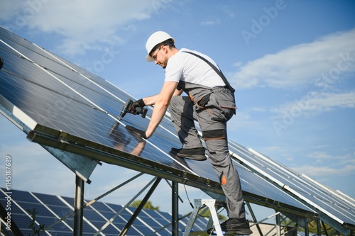 Wallpaper Mural Male worker in uniform with a drill screwdriver in his hand near solar panels Torontodigital.ca
