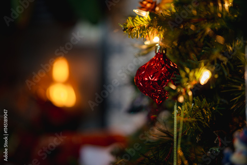 Red ornament on a Christmas tree with a fireplace in the background 