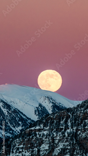 Salida de la luna llena en un paisaje de invierno. Montañas nevadas en los pirineos catalanes, con un atardecer rojizo.