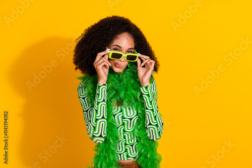 Young woman with curly hair poses in green top against vibrant yellow background photo