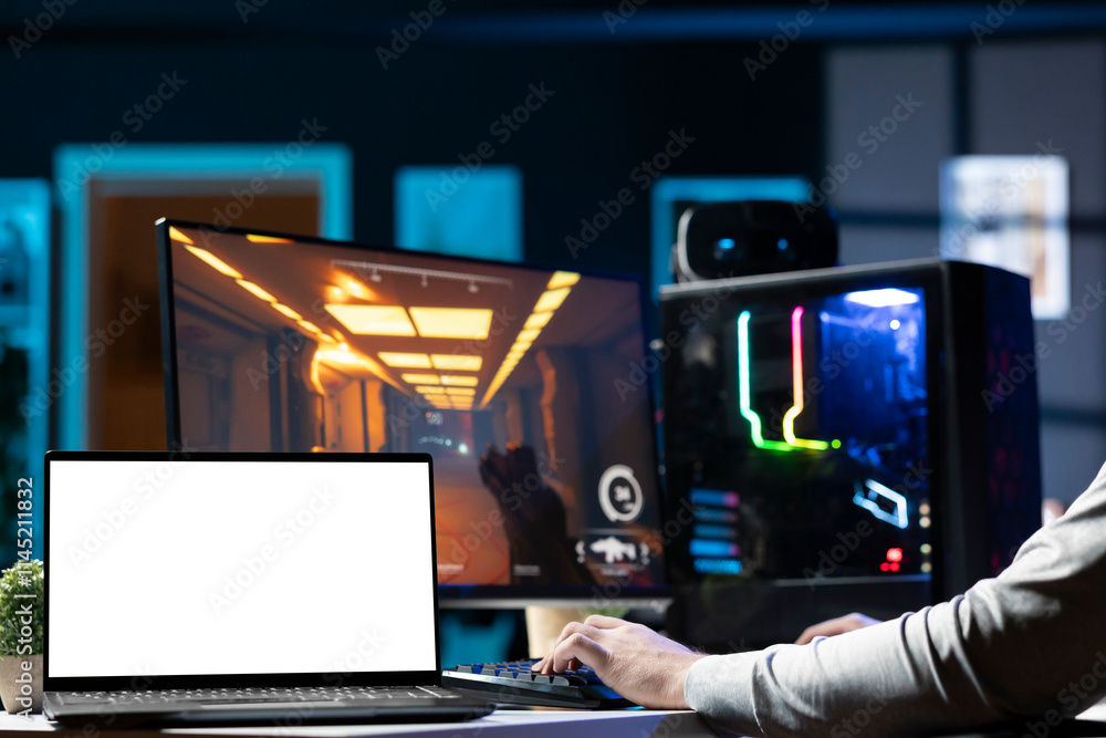 Man sitting on gaming chair using mockup laptop, relaxing by playing videogame on PC at computer desk late at night. Isolated screen notebook next to gamer enjoying game on computer Man sitting on gaming chair using mockup laptop, relaxing by playing videogame on PC at computer desk late at night. Isolated screen notebook next to gamer enjoying game on computer